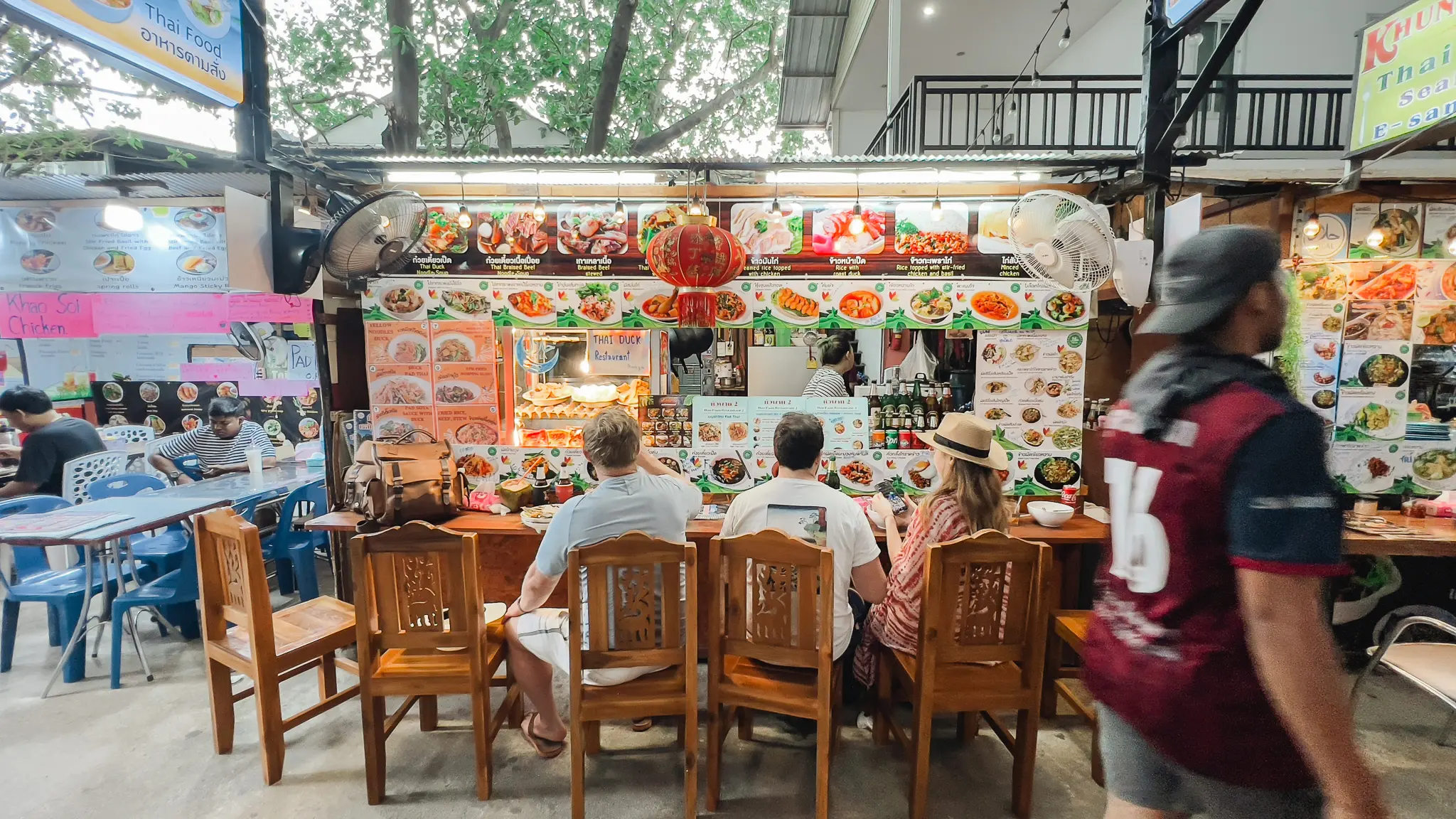 Touristes dégustant des plats thaïlandais sur un marché nocturne animé
