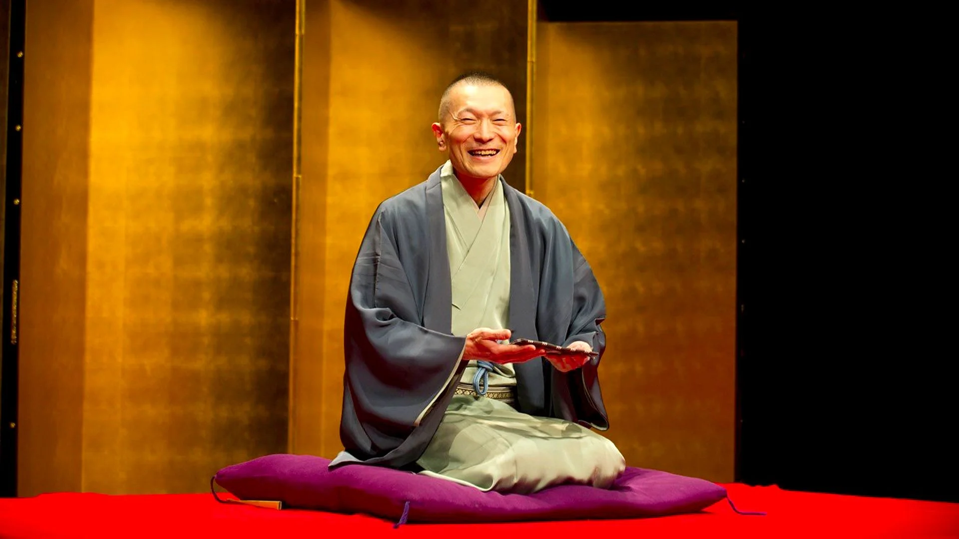 Conteur traditionnel japonais de Rakugo sur scène avec un éventail