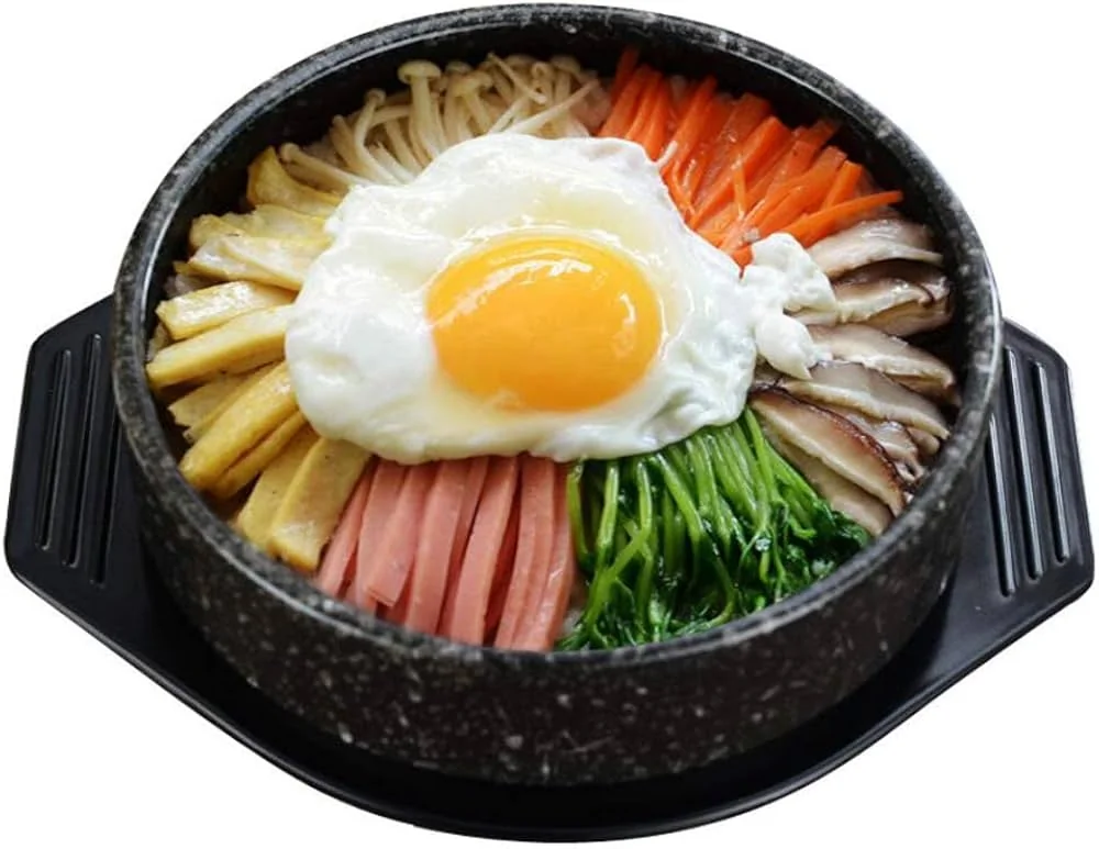 Dolsot bibimbap servi dans un bol en pierre noir brûlant.