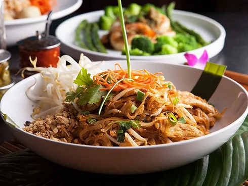 Plat de nouilles de riz sautées au wok avec du poulet, des cacahuètes et du citron vert, une spécialité thaïlandaise