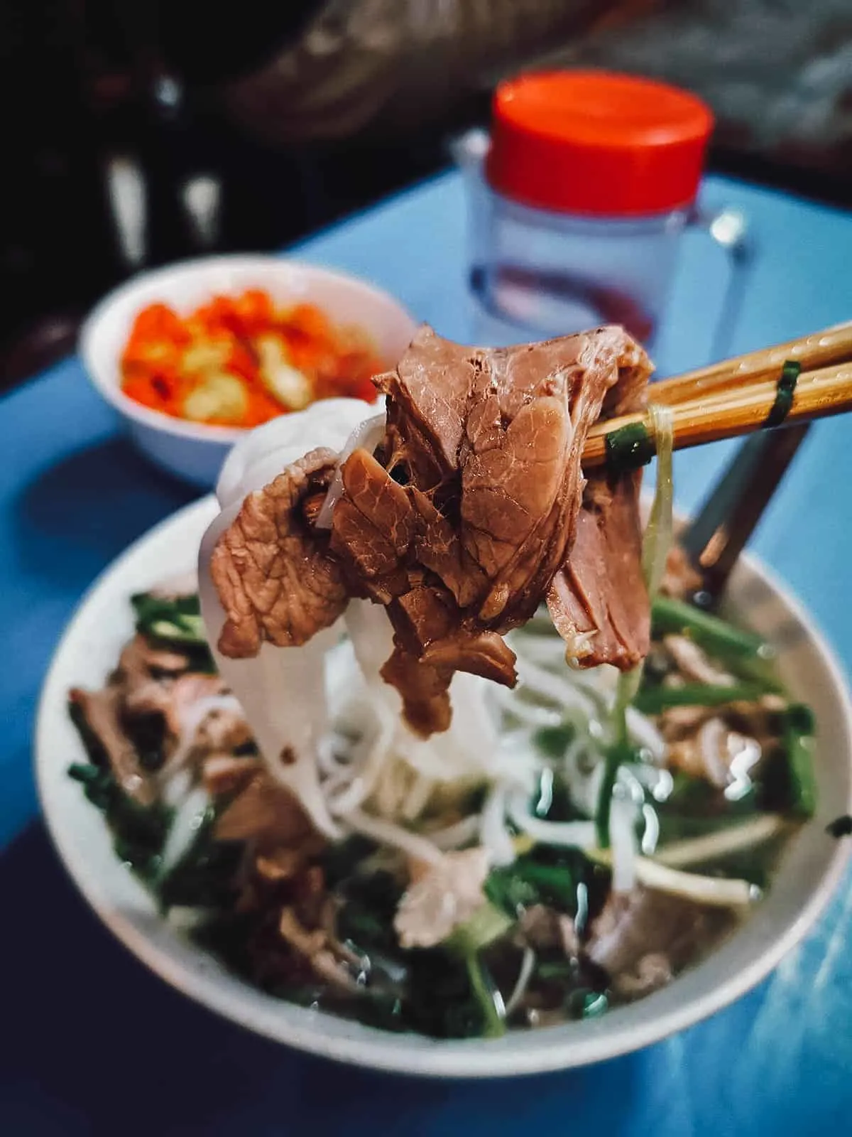 Bol de soupe Pho vietnamienne traditionnelle fumante avec bœuf et herbes fraîches