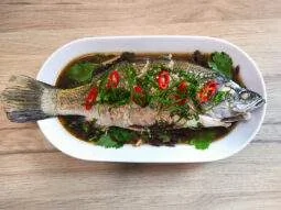 Poisson cuit à la vapeur avec une sauce soja légère, du gingembre frais et de la coriandre, typique de la cuisine asiatique saine