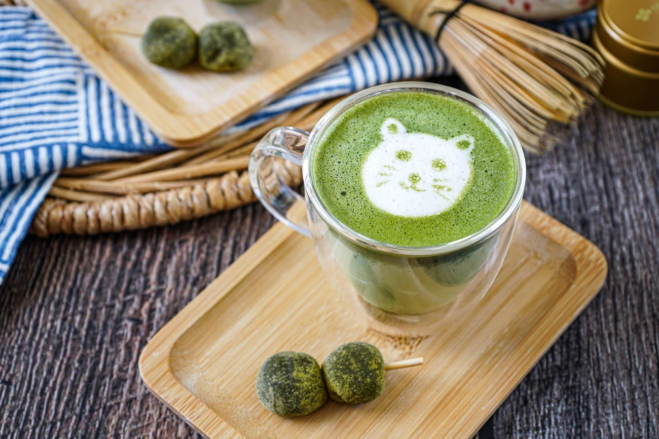 Tasse de thé matcha japonais posée à côté de volumes de mangas sur une table en bois