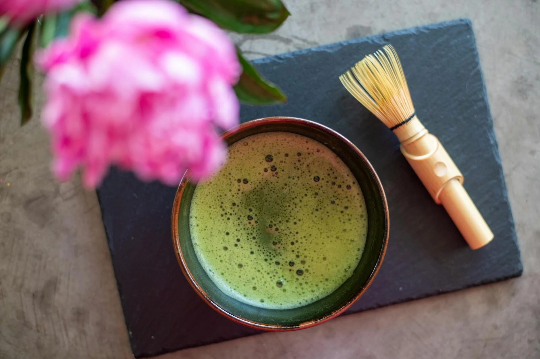 Un bol de thé matcha traditionnel avec un fouet en bambou sur une table
