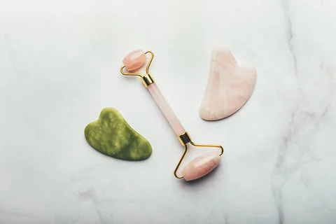 Comparaison visuelle entre un outil de massage en jade vert et un autre en quartz rose