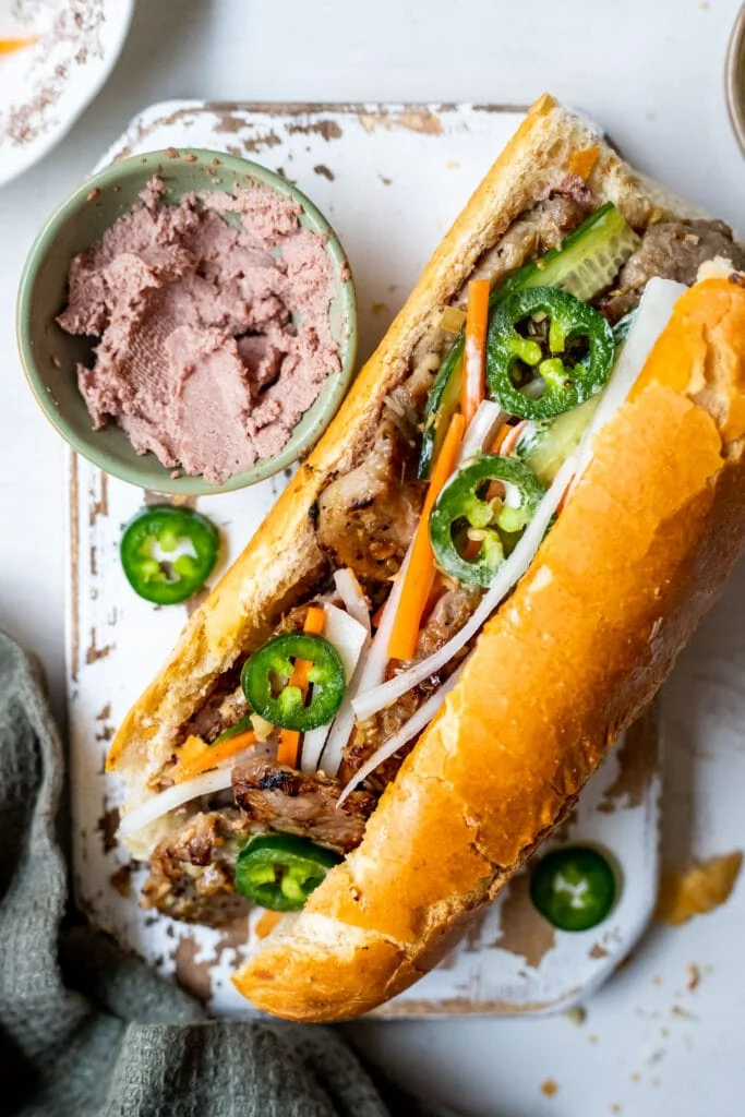 Préparation d'un Bánh Mì authentique au porc à la citronnelle avec pickles et pâté