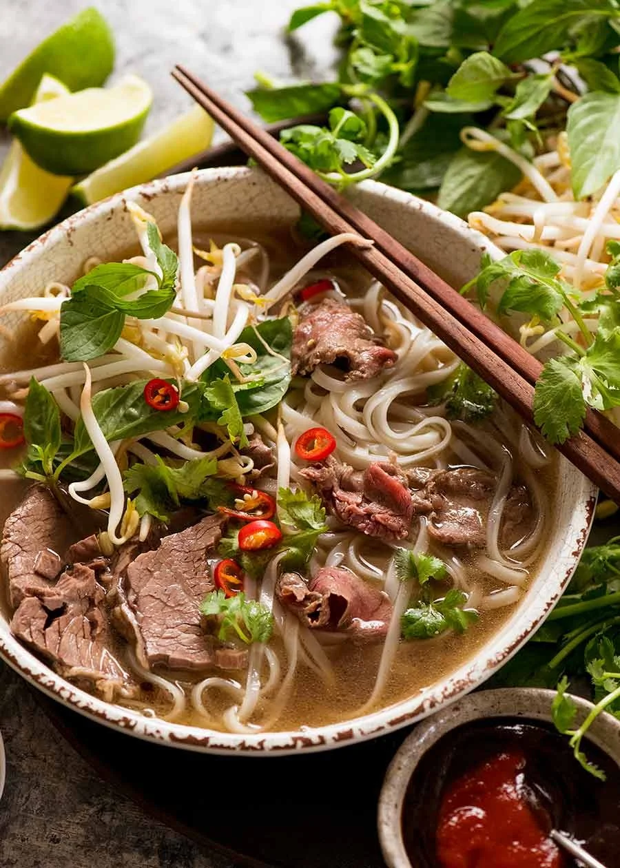 Bol de soupe Pho vietnamienne authentique avec bœuf tranché finement, nouilles de riz et herbes fraîches