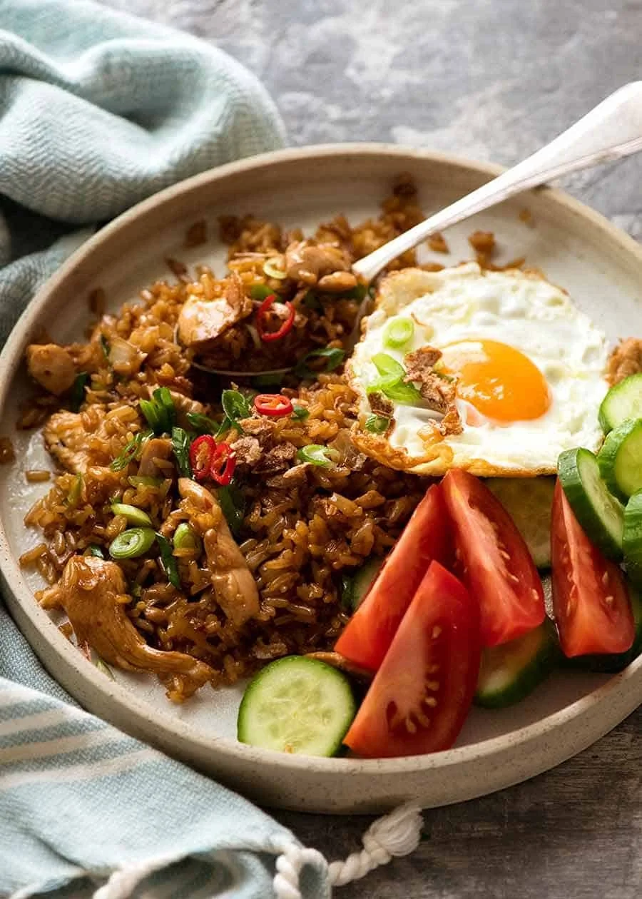 Assiette traditionnelle de Nasi Goreng avec œuf au plat, concombre et tomates