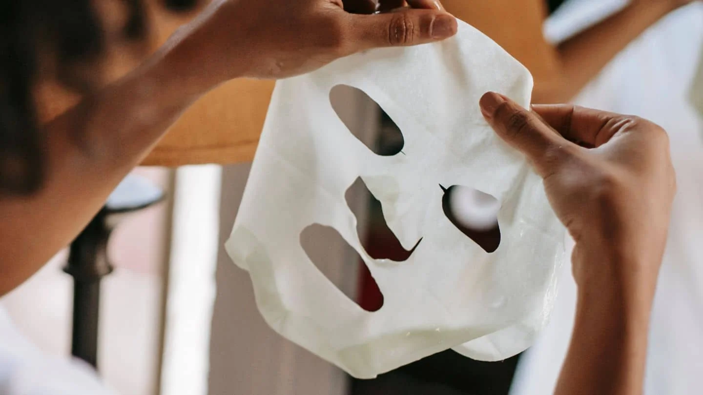 Femme portant un masque en tissu hydratant dans le cadre de sa routine de layering coréen.