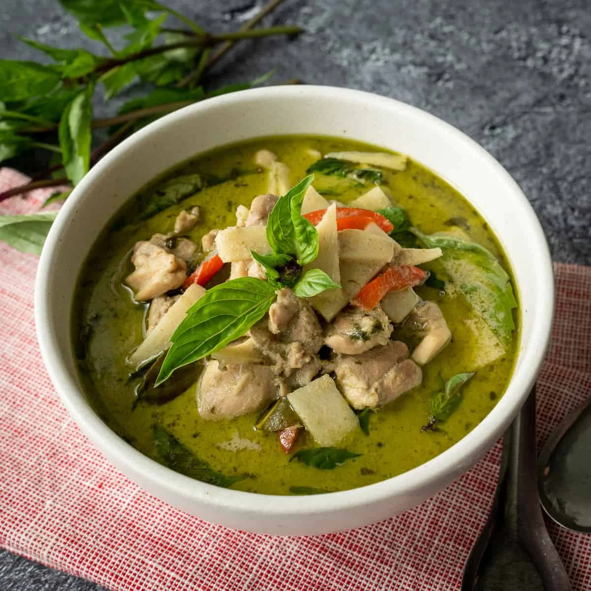 Bol de curry vert thaïlandais authentique garni de feuilles de basilic frais