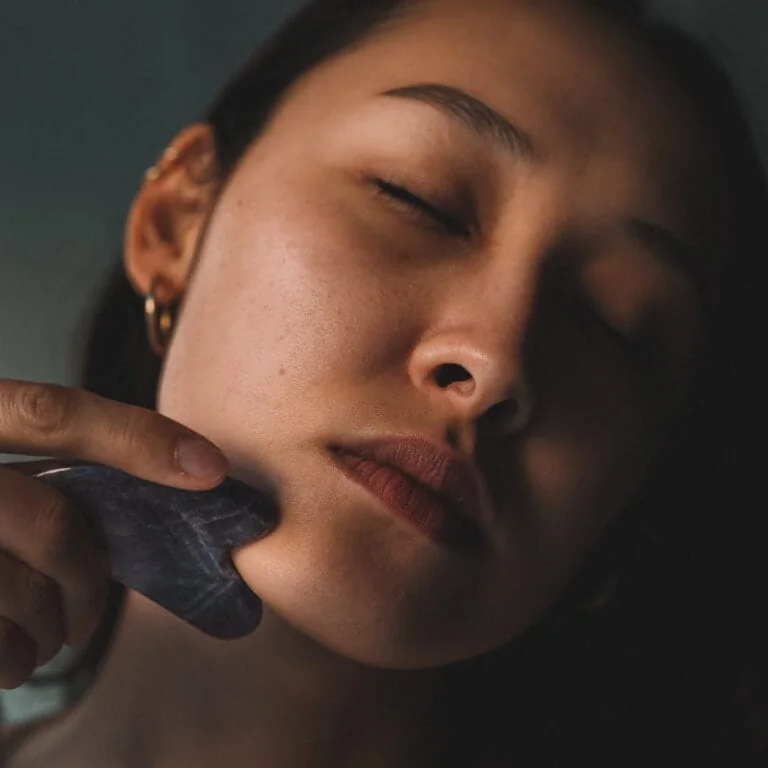 Femme utilisant un gua sha en améthyste sur la mâchoire