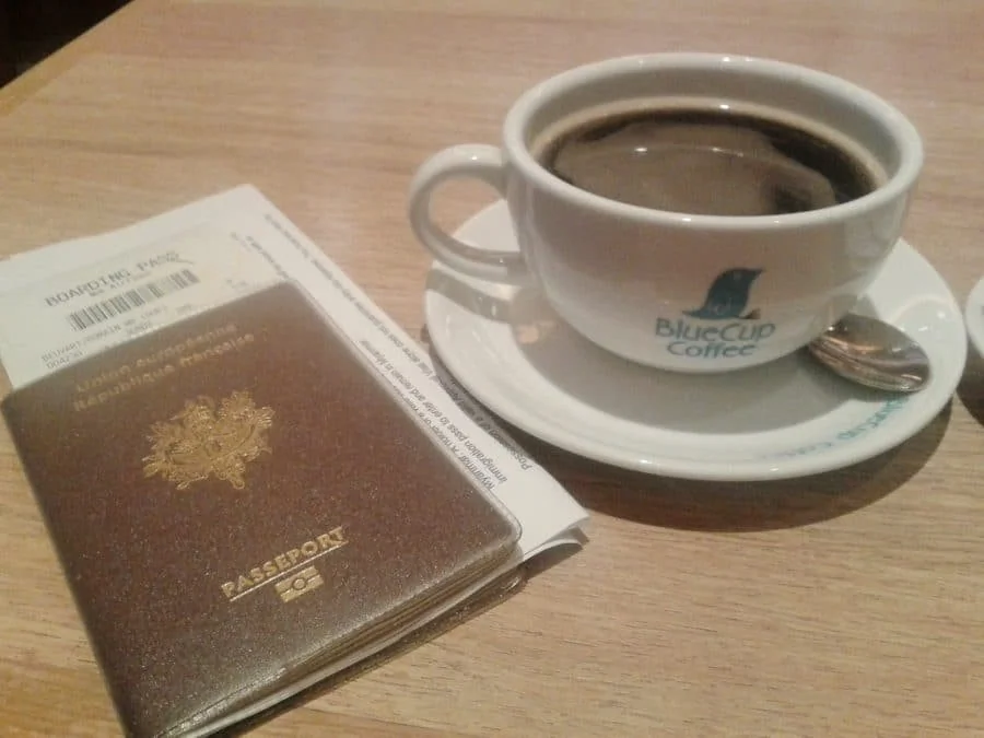 Passeport français et café à l'aéroport avant un vol vers l'Asie