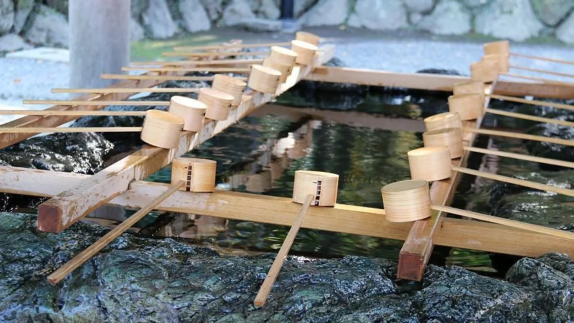 Rituel de purification à l'eau dans un sanctuaire de Kyoto avec une louche en bambou
