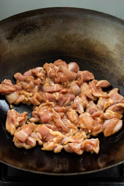 Morceaux de poulet en train de dorer dans un wok chaud