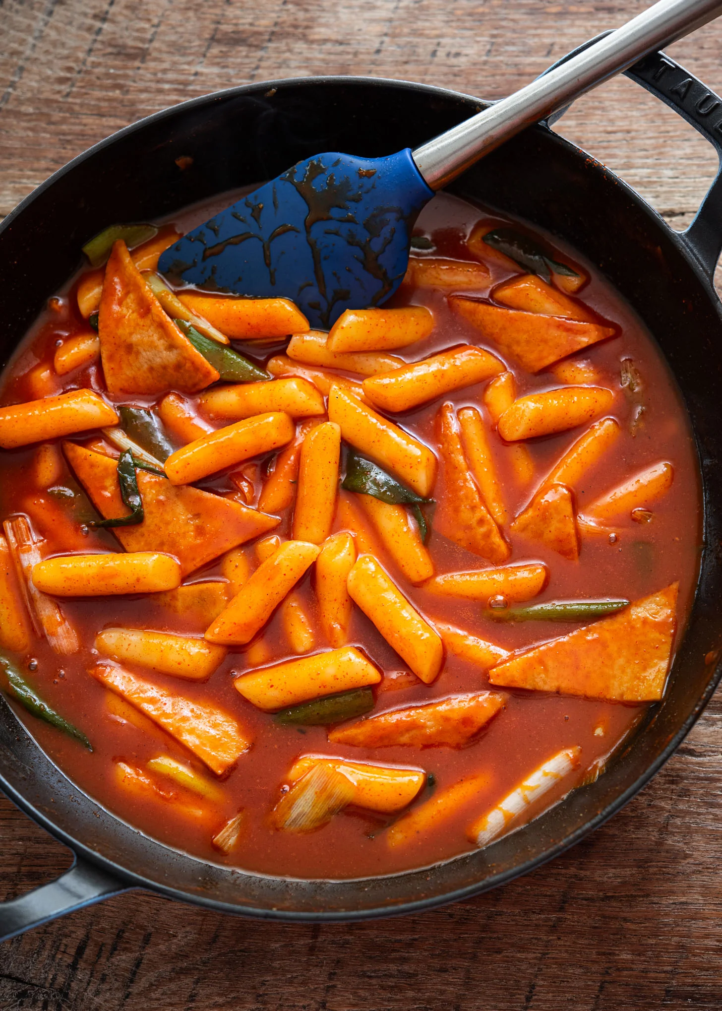 Plat de tteokbokki coréen authentique dans une poêle avec sauce rouge brillante et ciboule