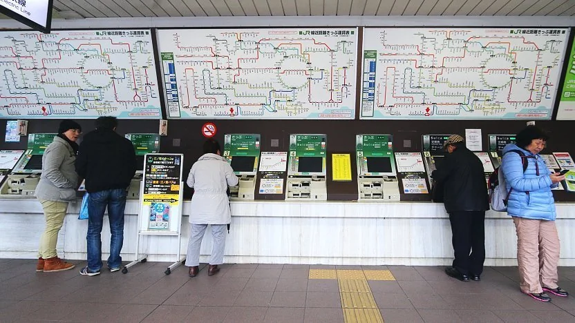 Voyageur utilisant une borne automatique JR dans une gare japonaise